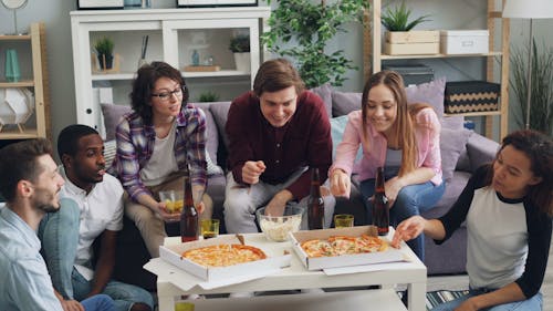 Group of friends eating pizza in living room