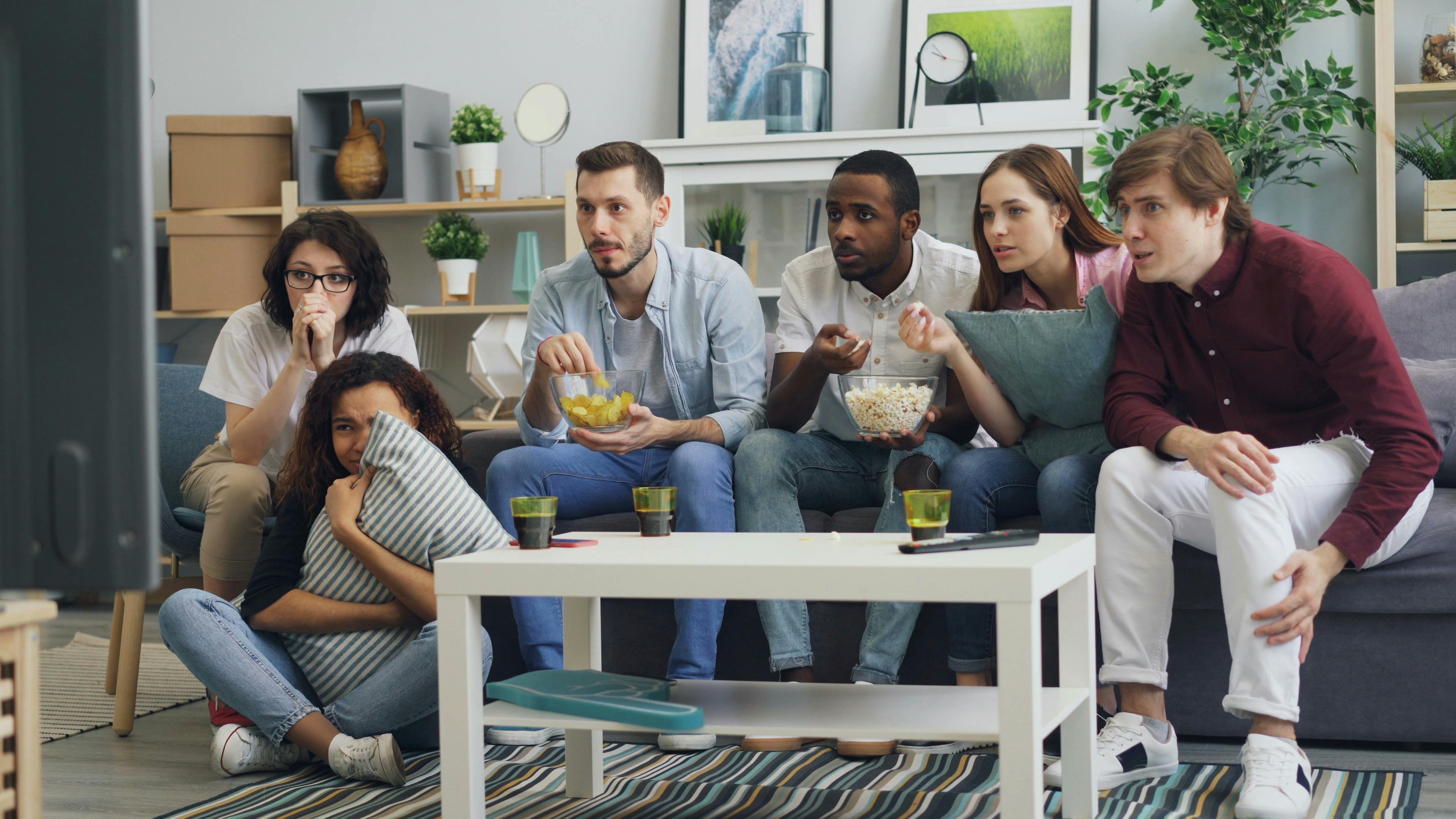 a group of people sitting on a couch watching tv