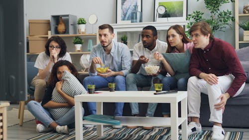 A group of people sitting on a couch watching tv