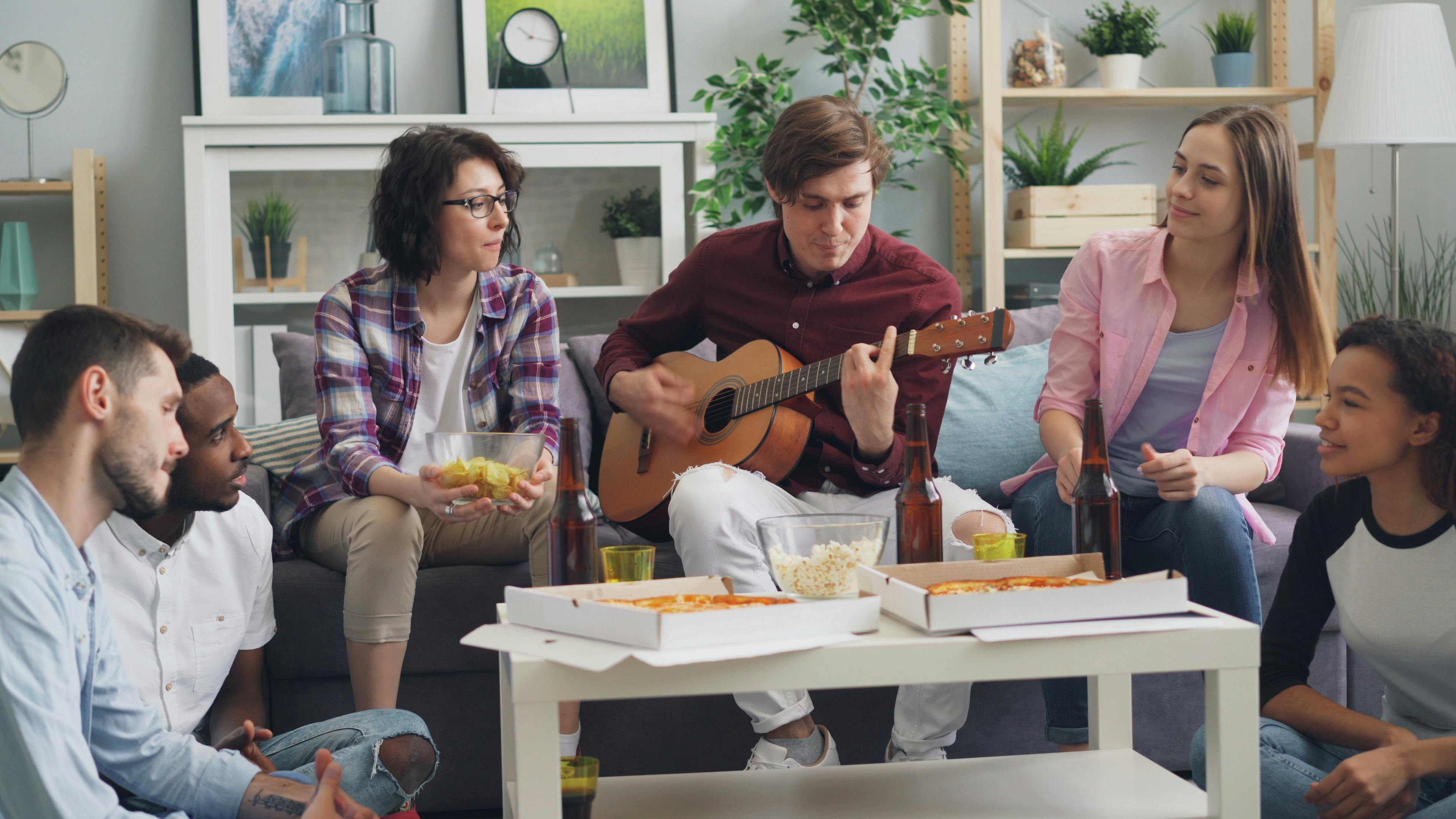 a group of people sitting around a table playing guitar