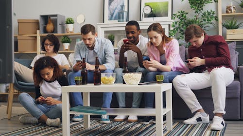 A group of people sitting on a couch and using their cell phones