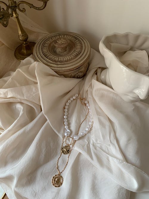 A white cloth with a gold necklace and a vase
