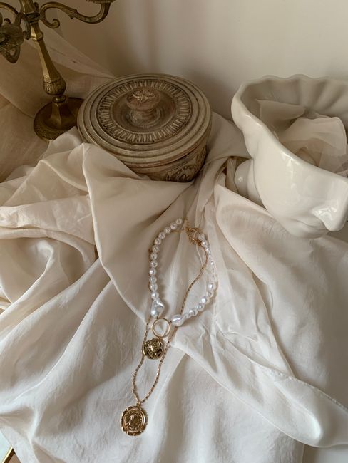 A refined arrangement of pearls and jewelry on soft fabric, exuding elegance and luxury.