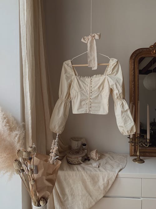 A white blouse hanging on a clothes rack