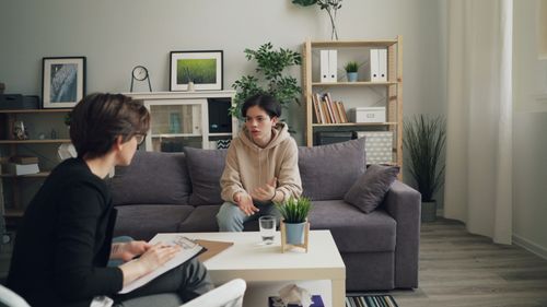 Free A teenager discusses issues with a therapist in a modern consultation room. Stock Photo