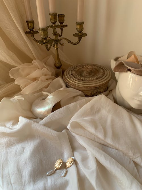 A white bed with a candle and a vase
