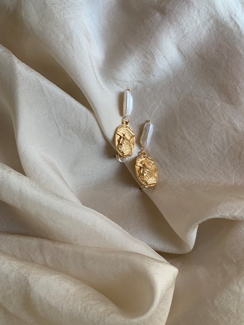 Golden earrings with pearls on a white cloth