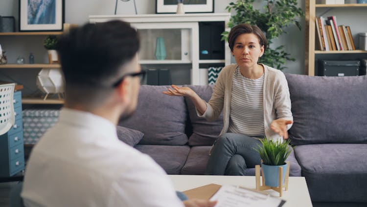 A Woman And Man Sitting On A Couch Talking