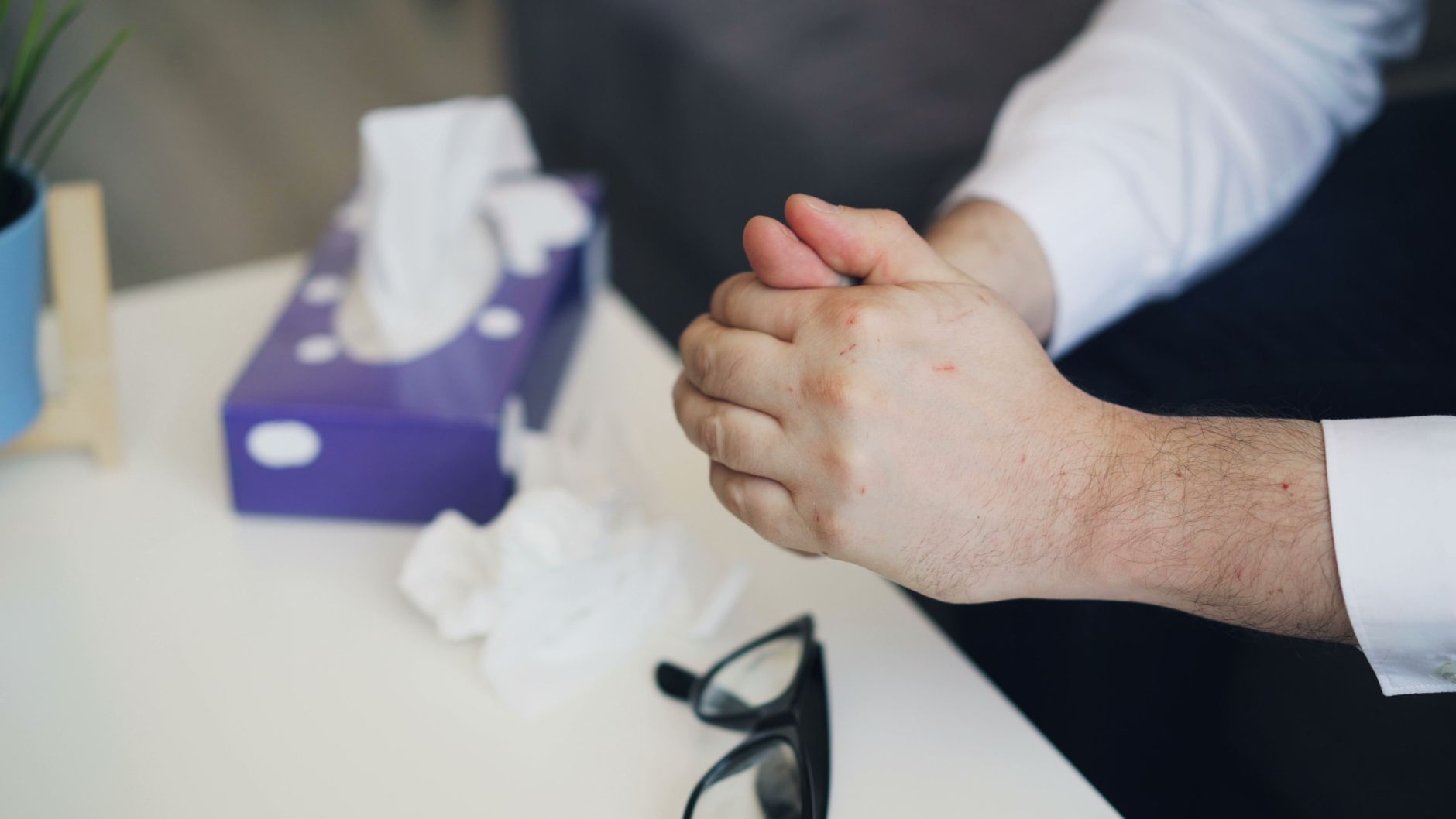 bromelain for long covid inflammation men — Hands nervously clasped near a tissue box, suggesting emotional stress or therapy session.