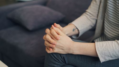 Free Close-up of clasped hands resting on lap indoors, suggesting relaxation or contemplation. Stock Photo