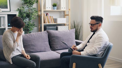 A man and woman sitting on a couch talking to each other