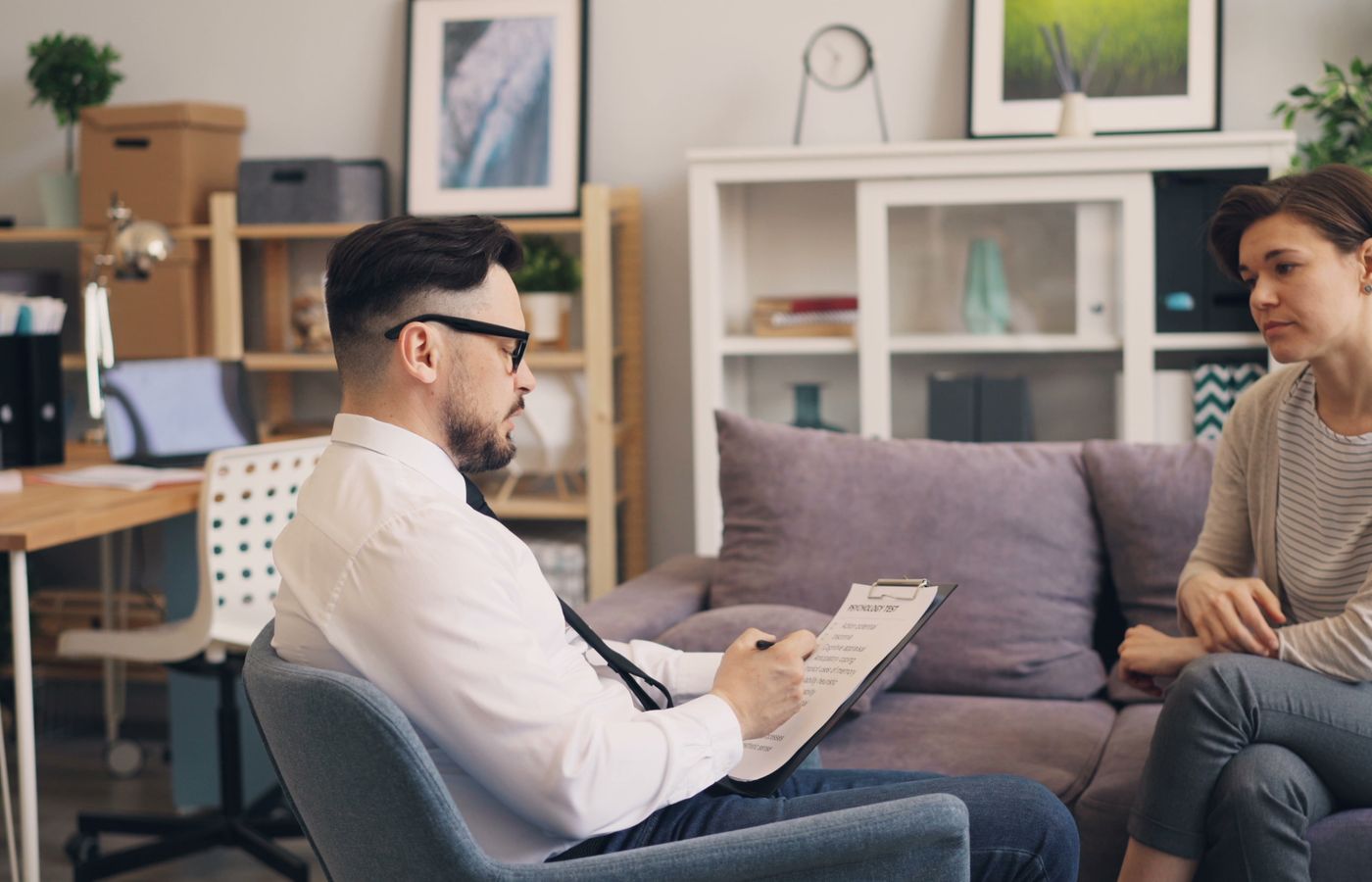 A therapist engages in a consultation session with a female patient in a cozy office setting.