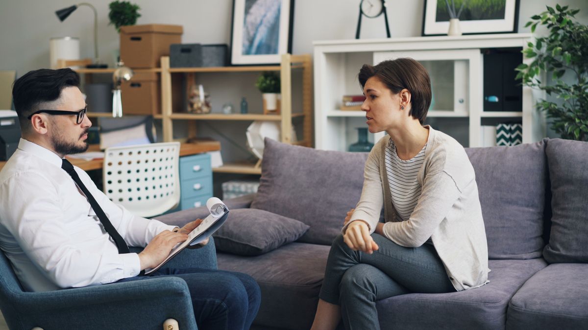 A practitioner with notes listening to a client seated opposite them.