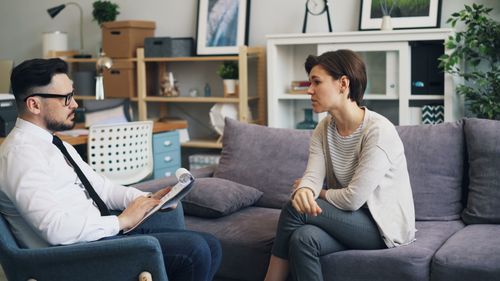 Free A therapist consults with a client during a counseling session on a sofa in an office setting. Stock Photo