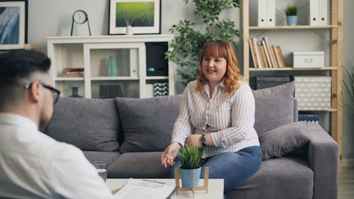 A woman sitting on a couch talking to a man
