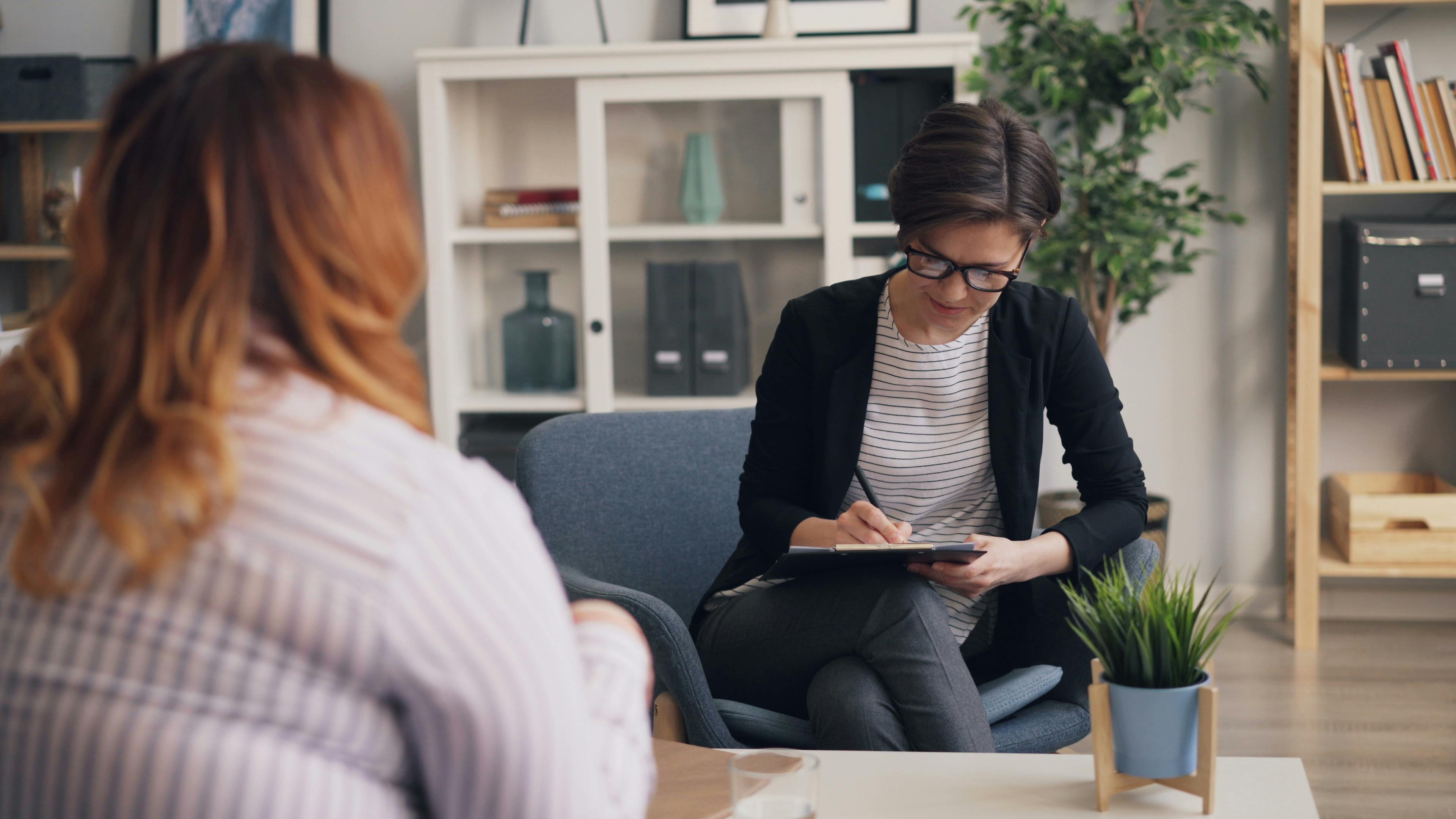 Woman Sitting in a Chair and Talking to Another Woman