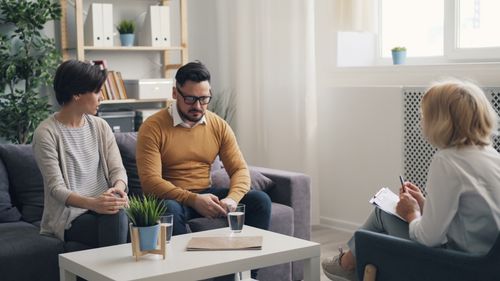 Free A couple in a psychotherapy session with a therapist in a cozy office. Stock Photo