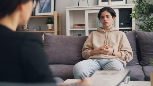 A woman sitting on a couch talking to a man