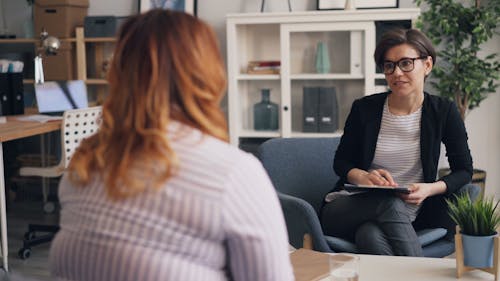 A woman sitting in an office talking to another woman