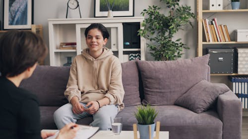 A woman sitting on a couch talking to a man