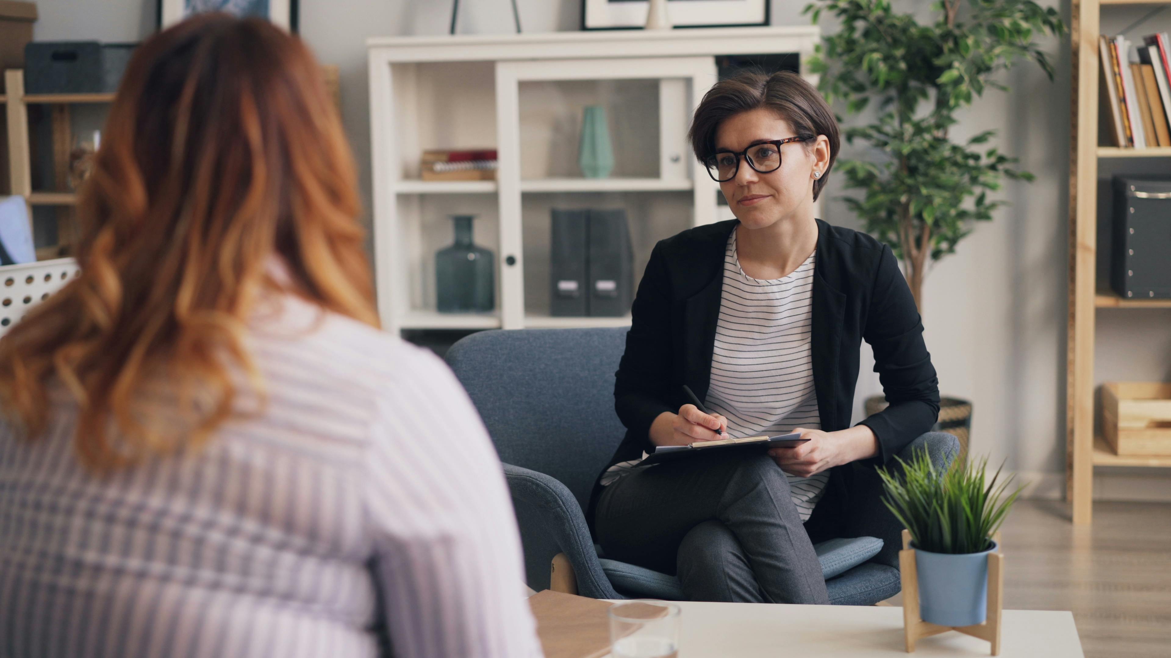 a woman sitting in a chair talking to another woman