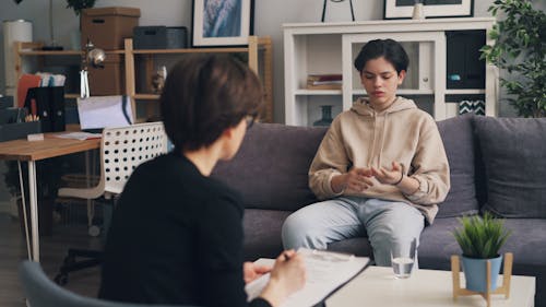 A woman sitting on a couch talking to a man