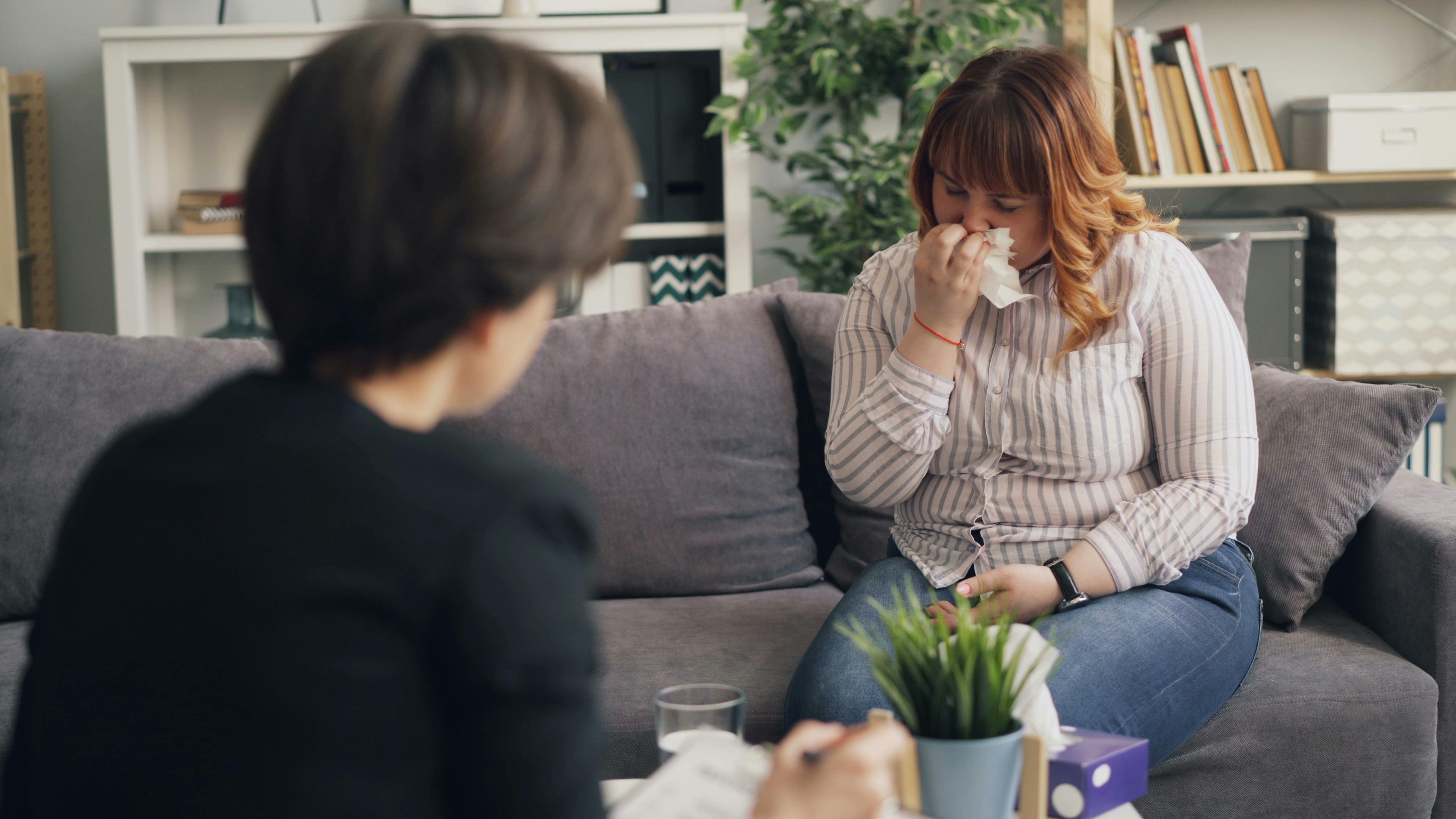 A woman in therapy expressing emotions during a counseling session indoors.