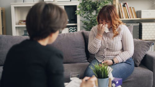 A woman sitting on a couch talking to another woman