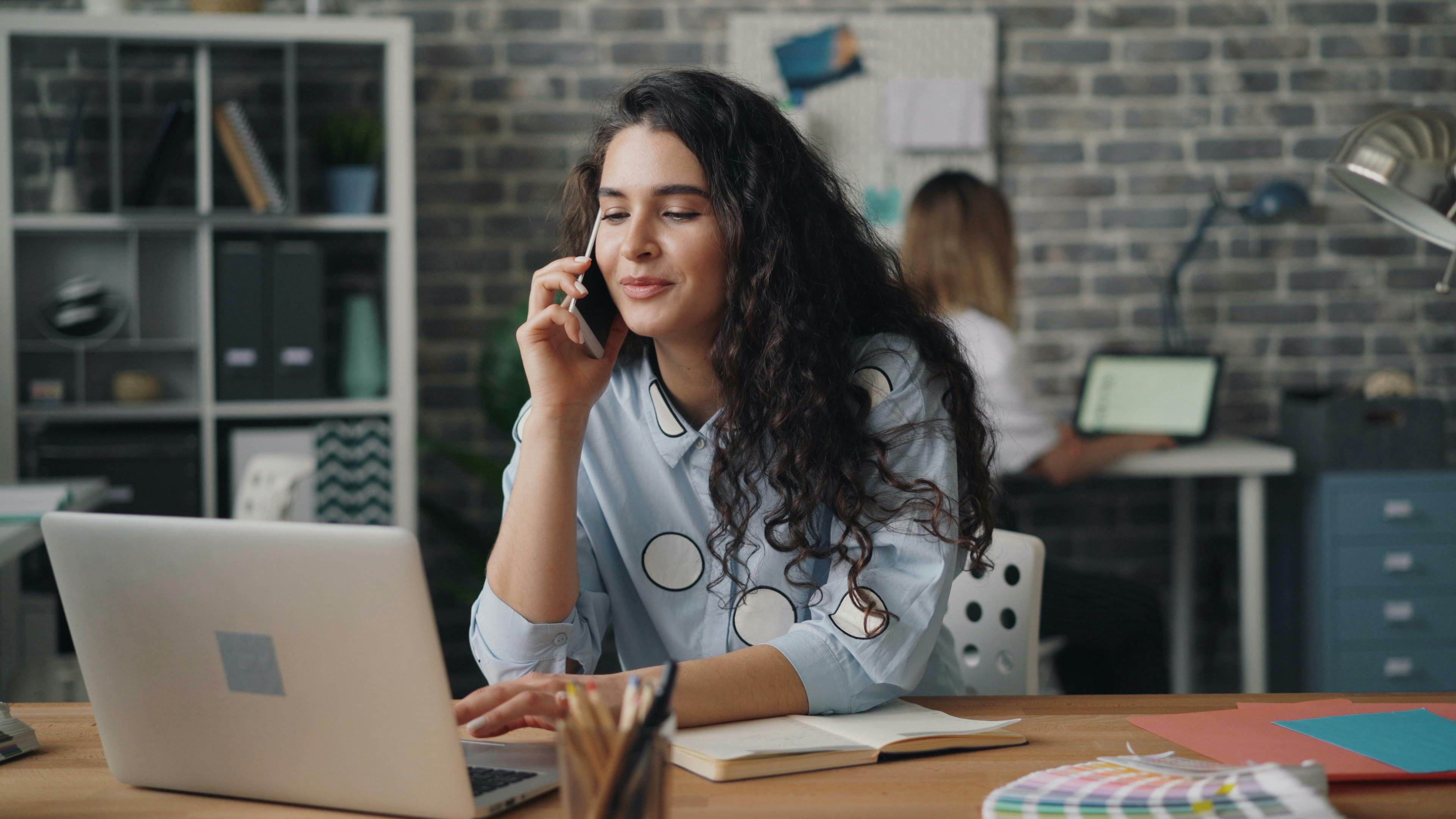 a woman on the phone in front of a laptop