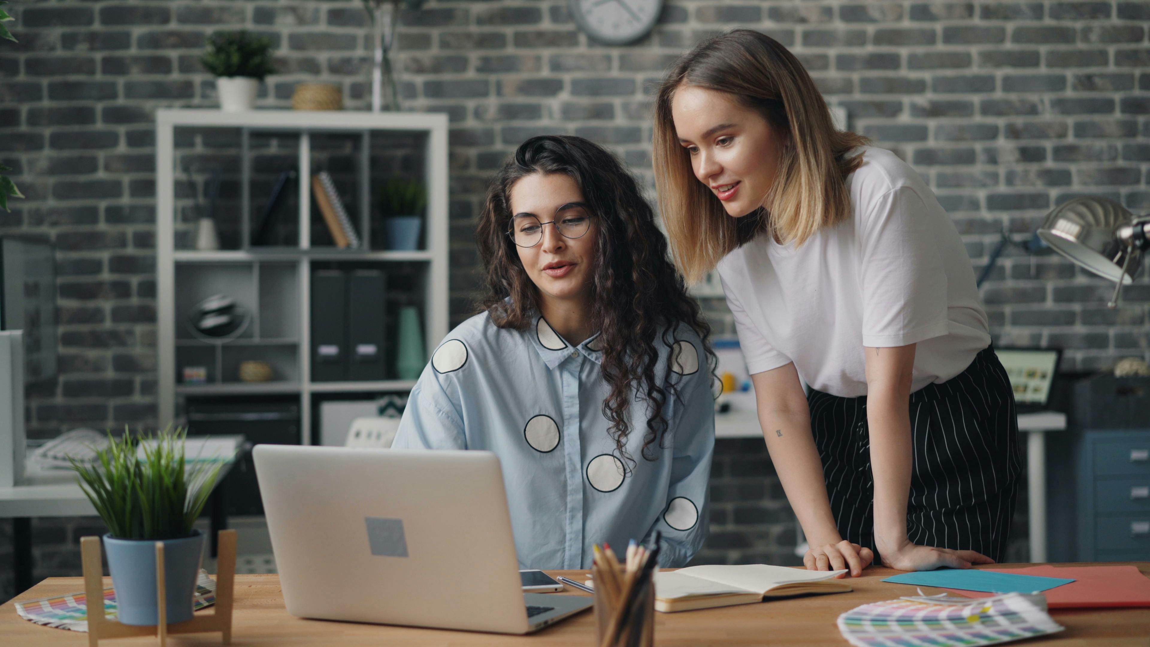 two women working on a laptop in an office