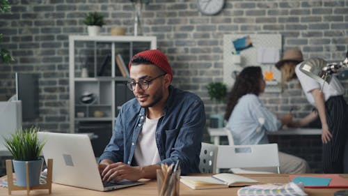 A man in a red hat is working on his laptop