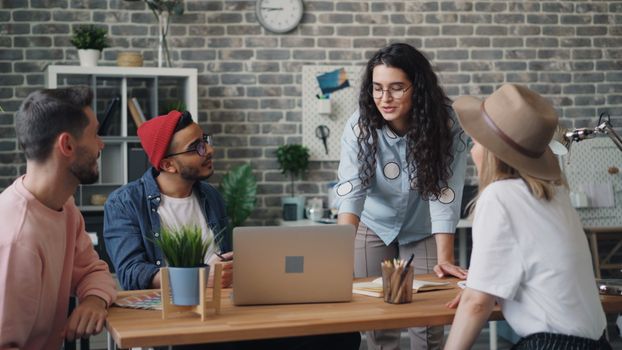A diverse group of creative professionals discussing ideas in a modern office with a laptop.
