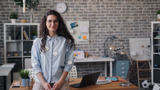 Smiling woman in a modern office space with a laptop and stylish decor.