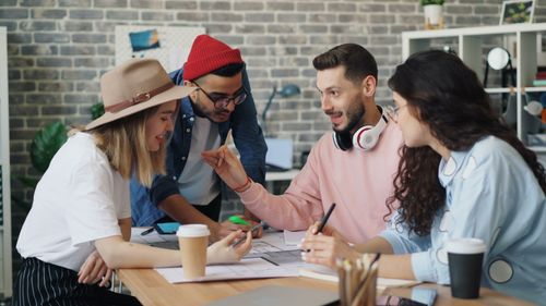 Free Young diverse team brainstorming together in a modern office setting, promoting teamwork and innovation. Stock Photo
