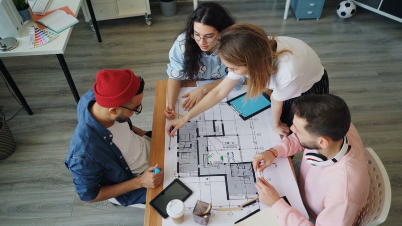 Four professionals gathered around a table reviewing architectural blueprints