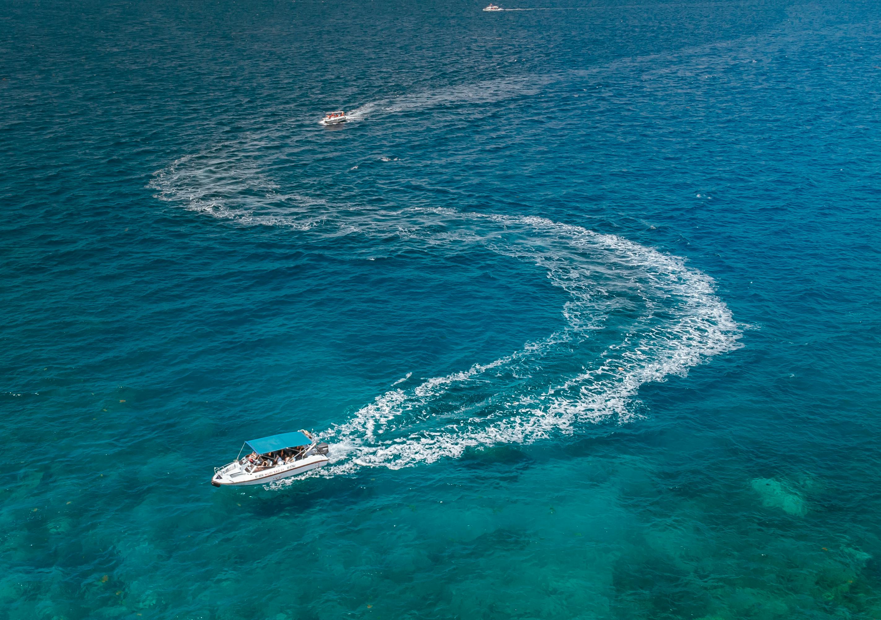 Aerial shot of boats creating a zigzag pattern on clear turquoise ocean water.