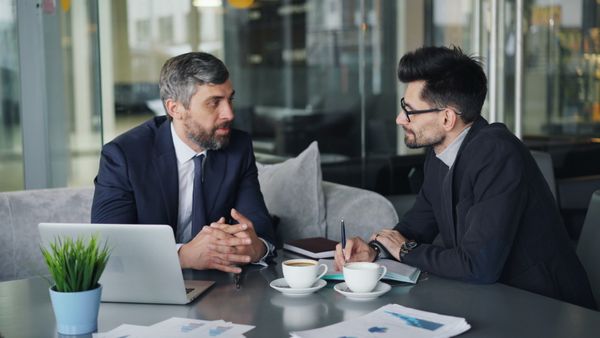 Two people reviewing paperwork and documents at a desk