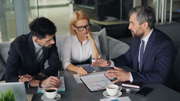 Professional colleagues engaged in a business meeting discussing strategy over coffee.