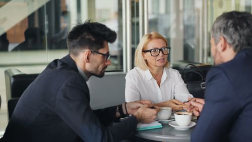 Free Professional team discussing ideas over coffee in a modern café setting. Stock Photo