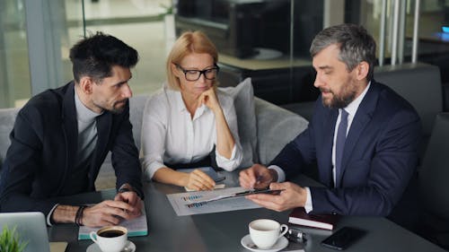 Three business people sitting at a table with a laptop