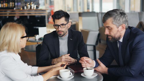 Three business people sitting at a table having coffee