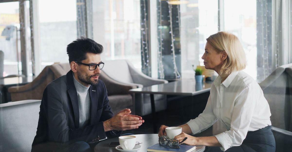 Businessman and businesswoman having a discussion over coffee in a stylish cafe setting.
