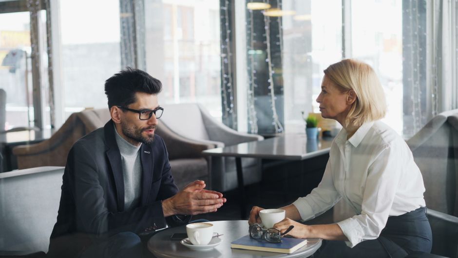 Un homme et une femme en pleine discussion professionnelle autour d'un café