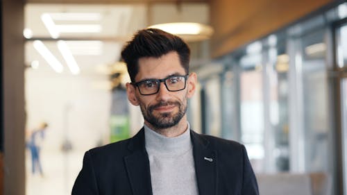 A man with glasses and a jacket standing in an office