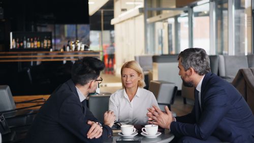 Free Business professionals engaged in a meeting at a café setting, discussing ideas. Stock Photo
