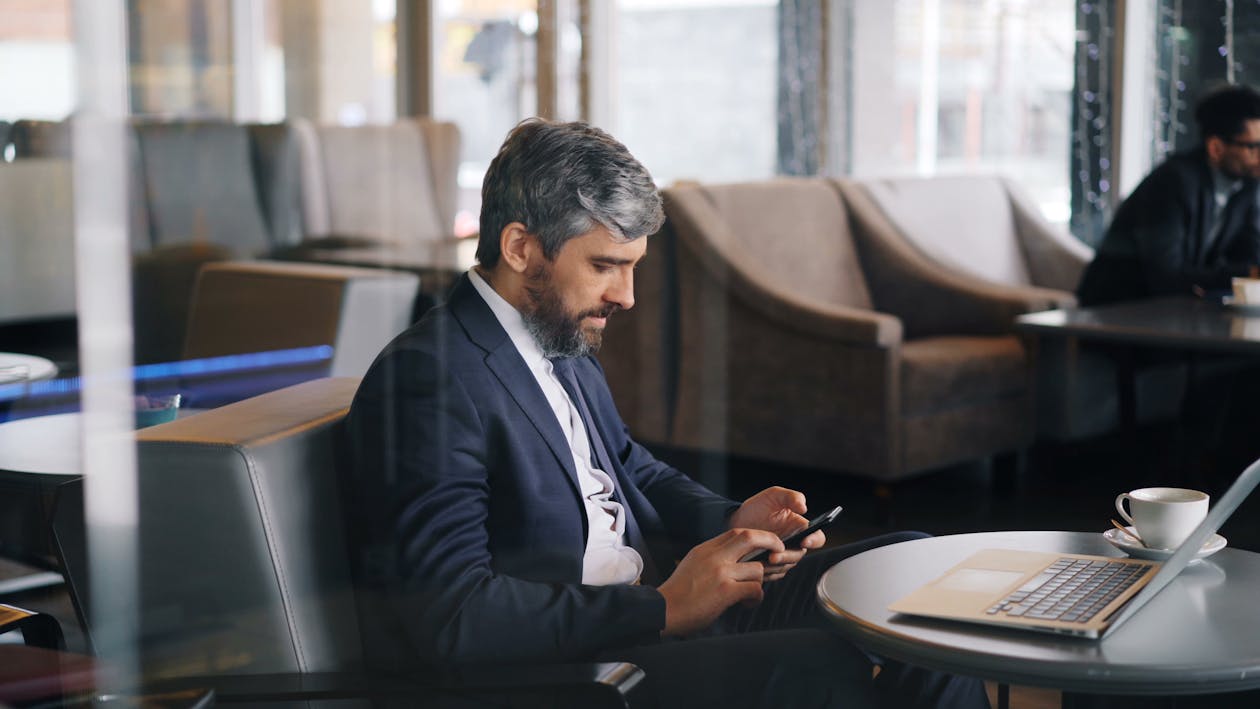 A man in a suit sitting at a table with a laptop