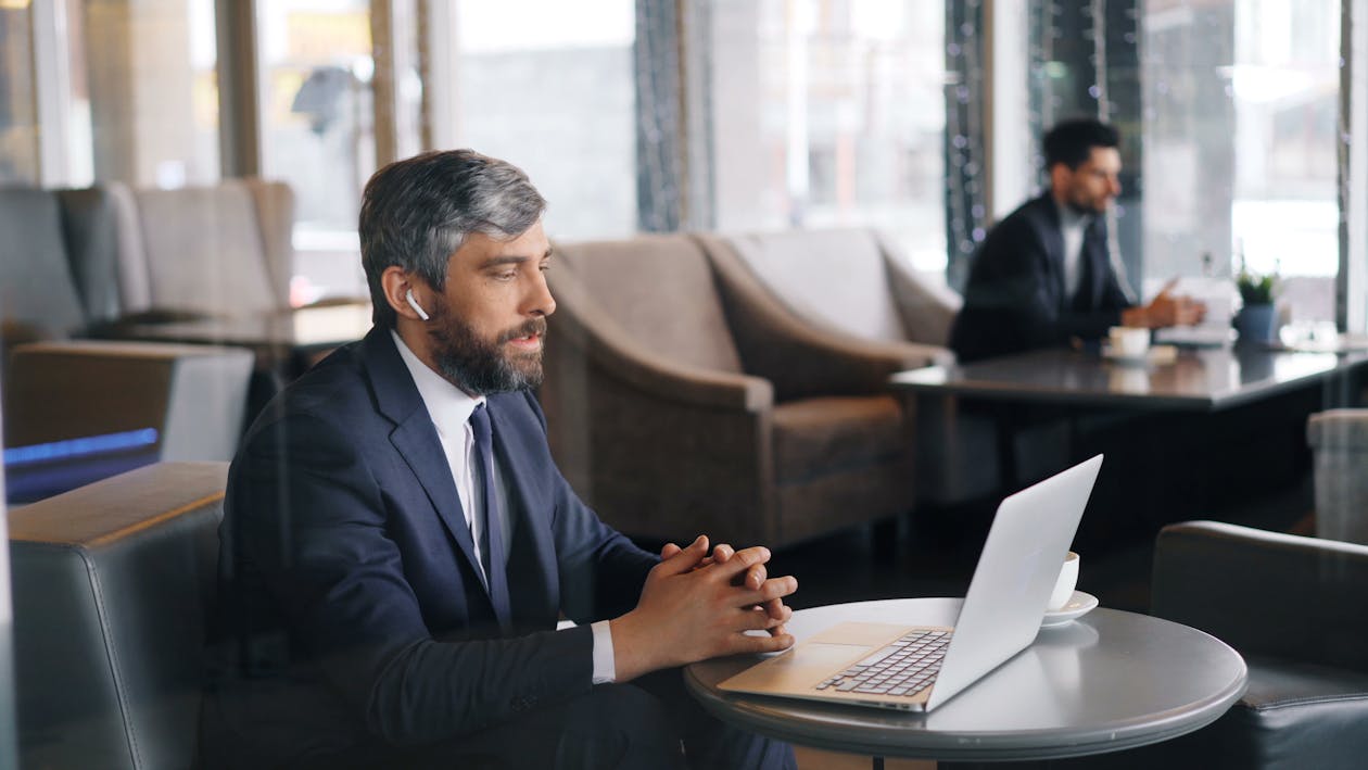 Two men in business attire sitting at a table with laptops