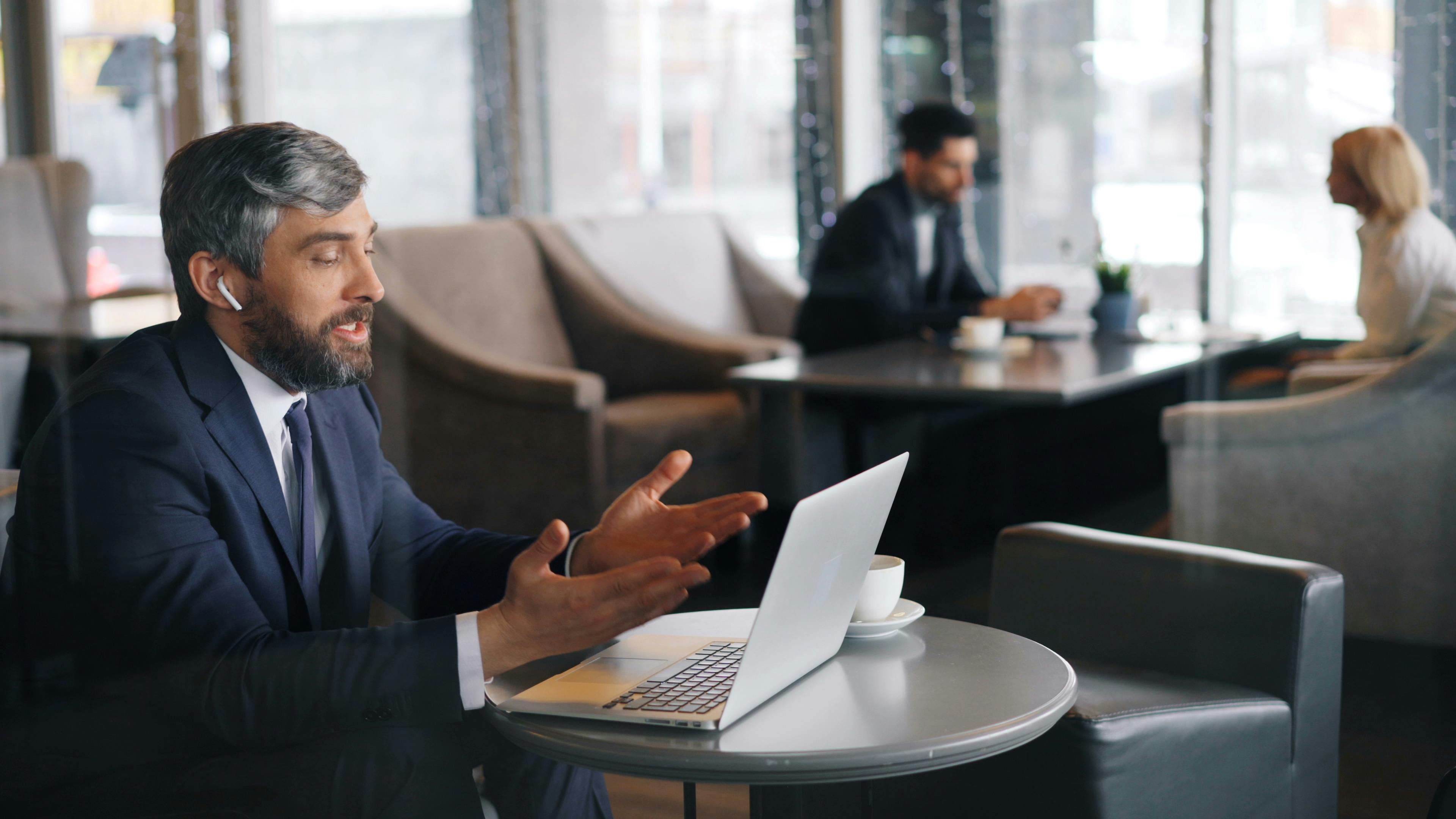 a man in a suit sitting at a table with a laptop