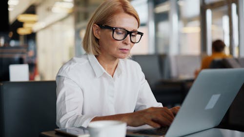 A woman in glasses is working on her laptop