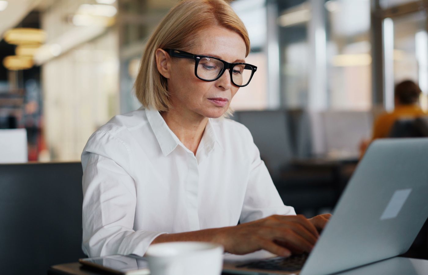 Focused woman using laptop in a café, epitomizing modern entrepreneurship.